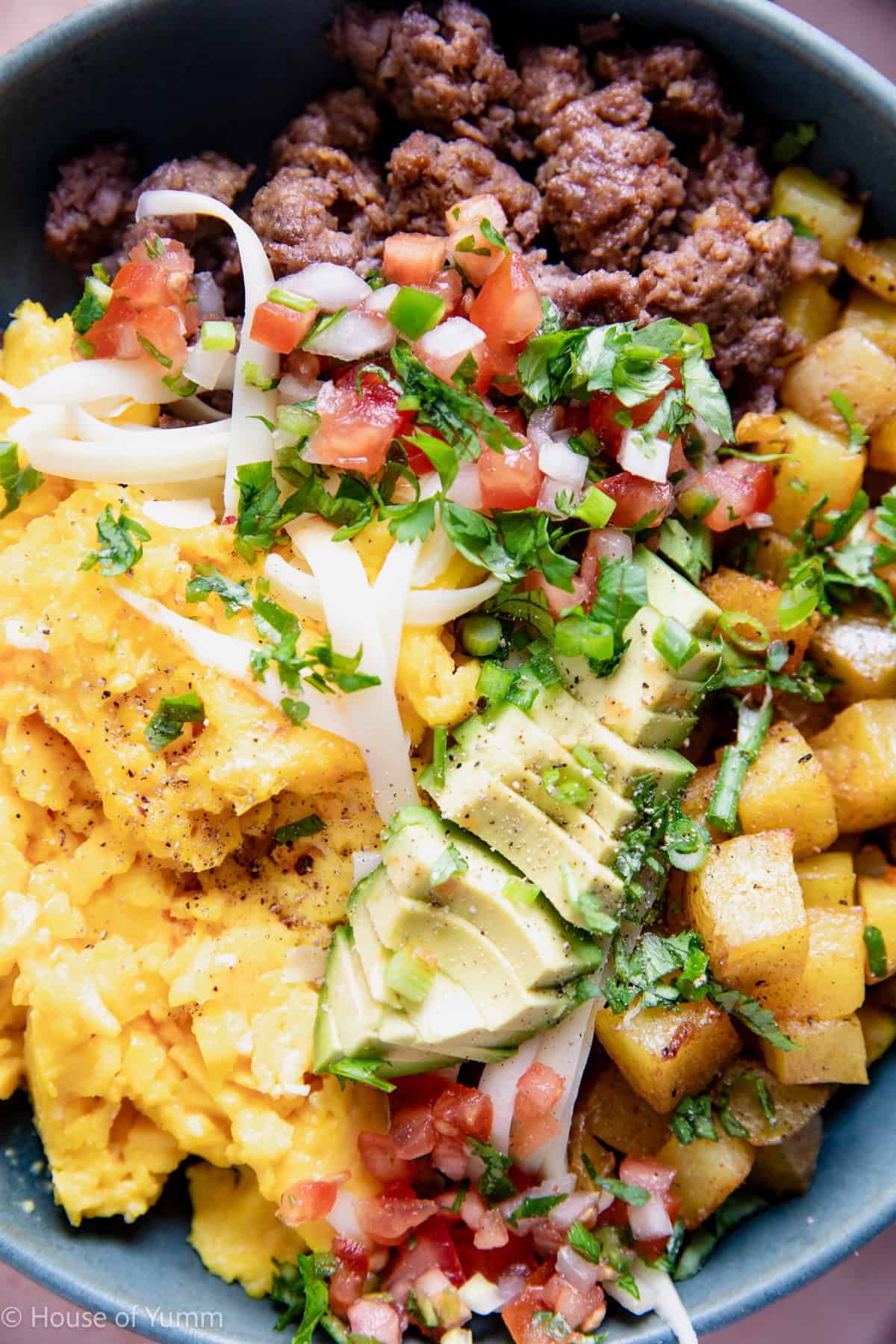Close up of a breakfast burrito bowl served with avocado and salsa.