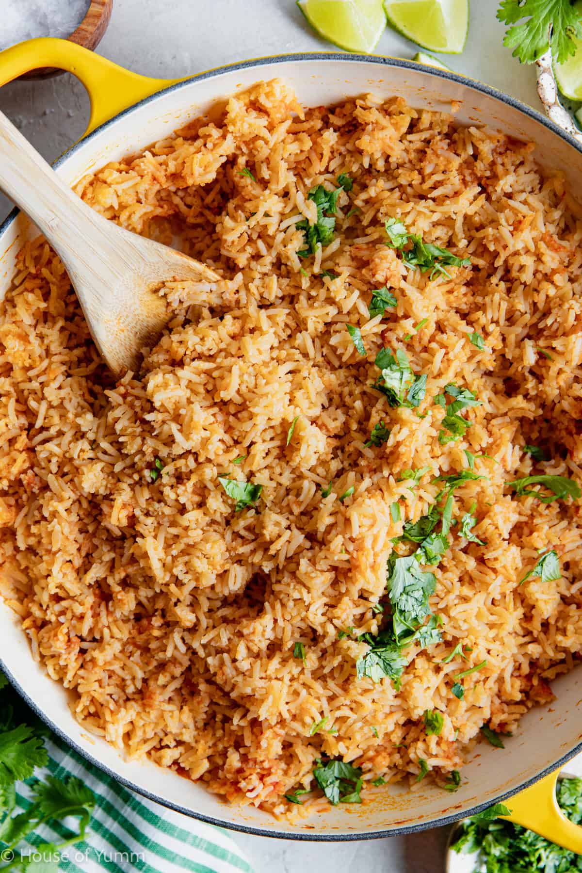 Restaurant style Mexican Rice in a skillet being served with wooden spoon.