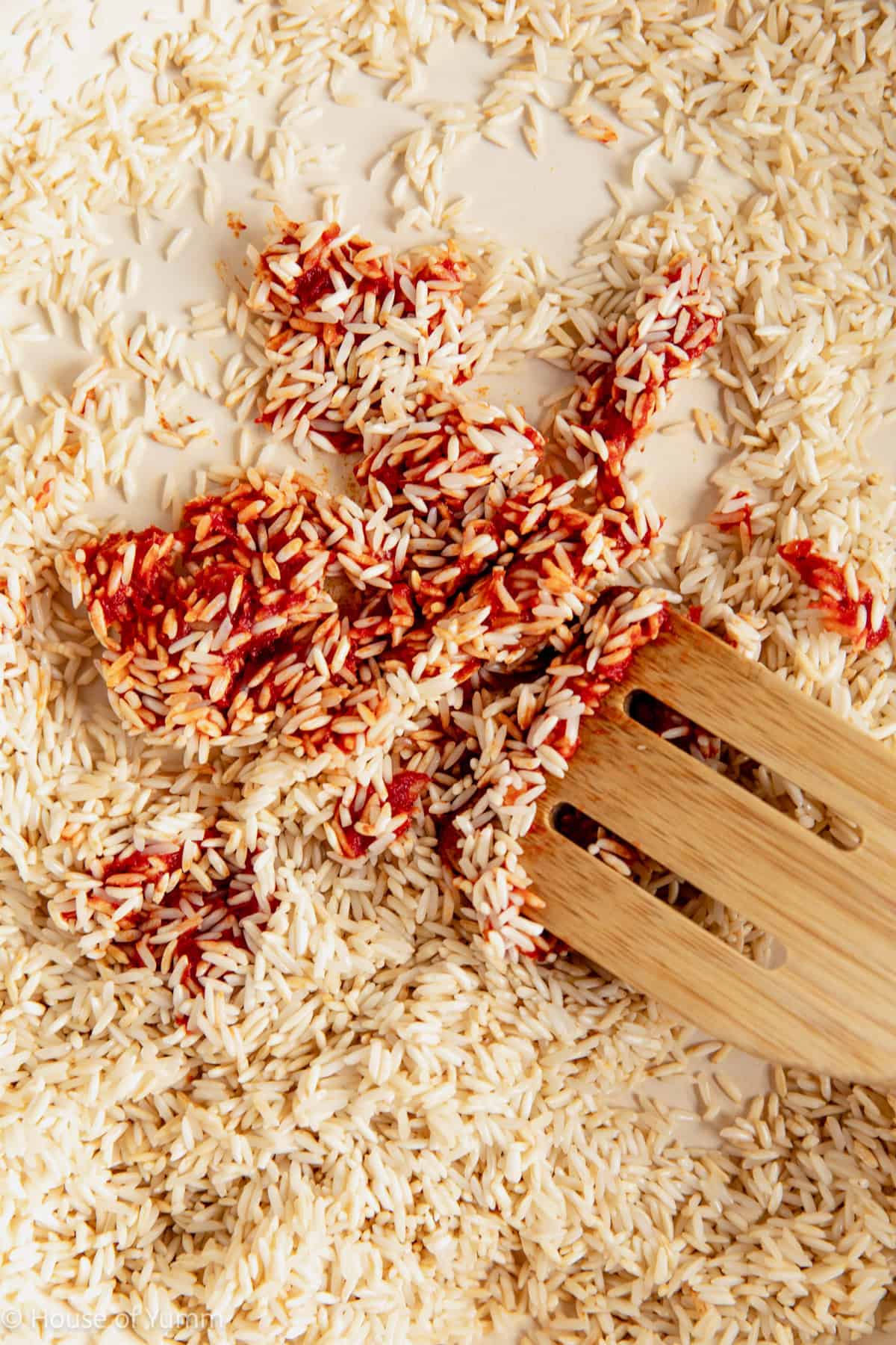 Stirring tomato paste into white rice.