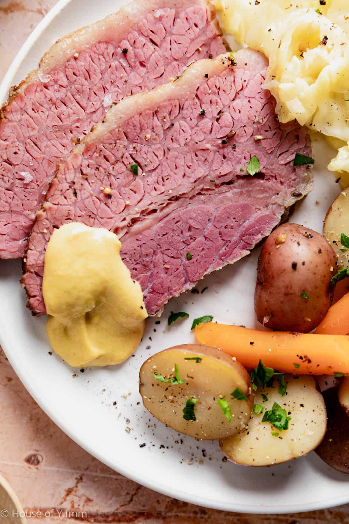 Corned beef slices on a plate with cabbage and vegetables.