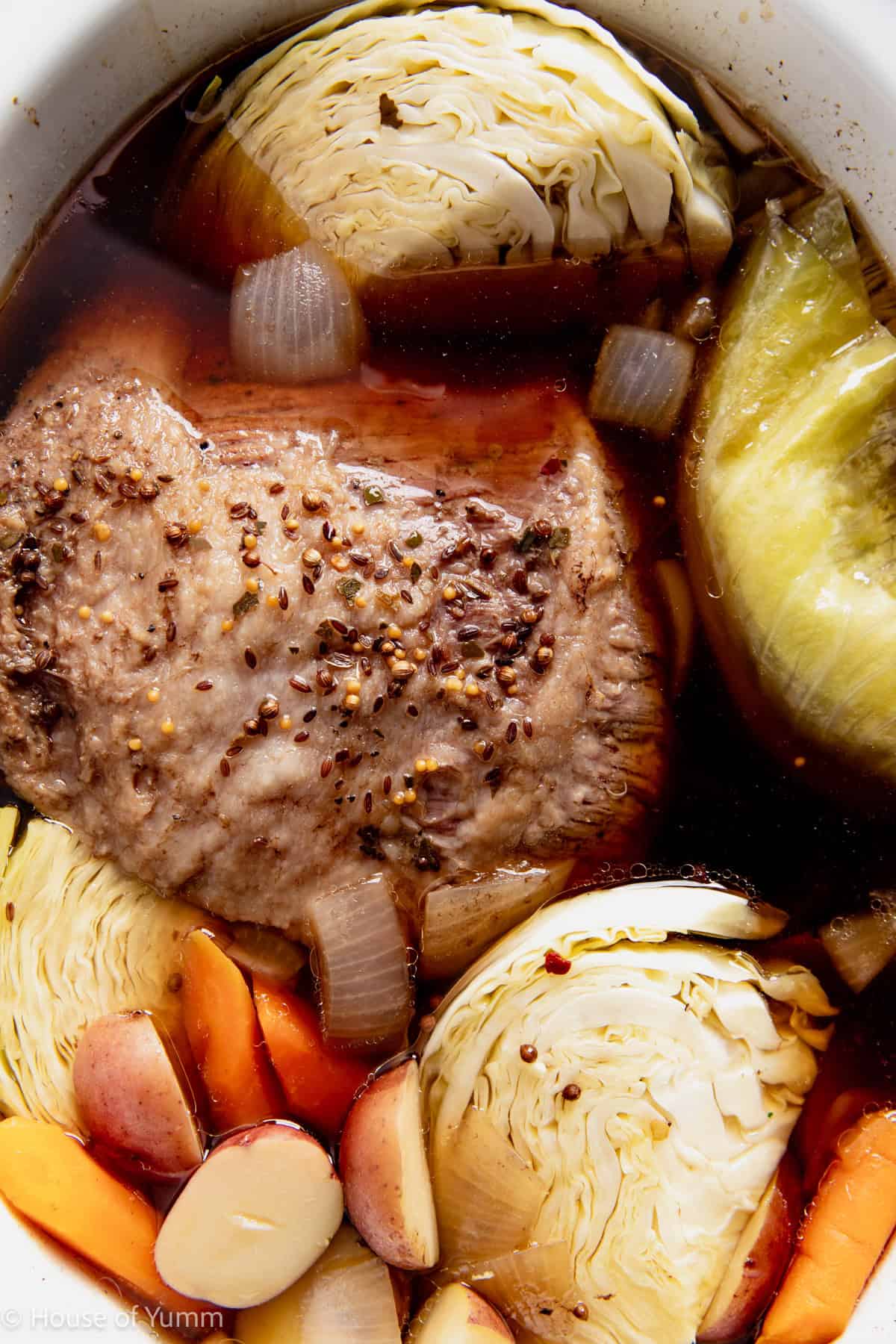 Corned beef cooked in a slow cooker with potatoes, carrots, and cabbage.