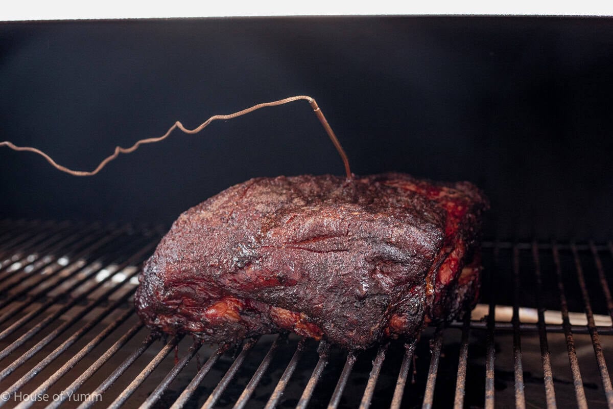 Pork butt in a smoker with a temperature probe in it.