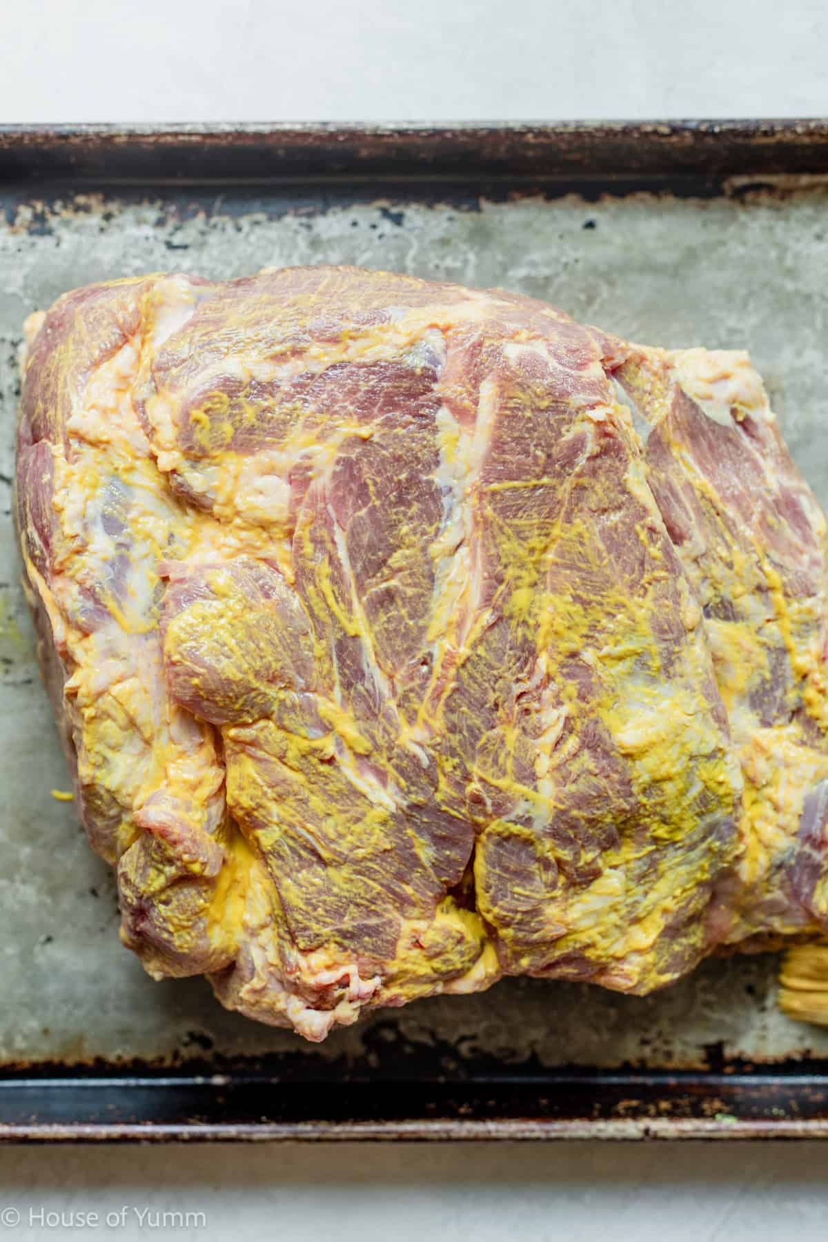 Pork shoulder rubbed with mustard as a binder before adding seasoning.