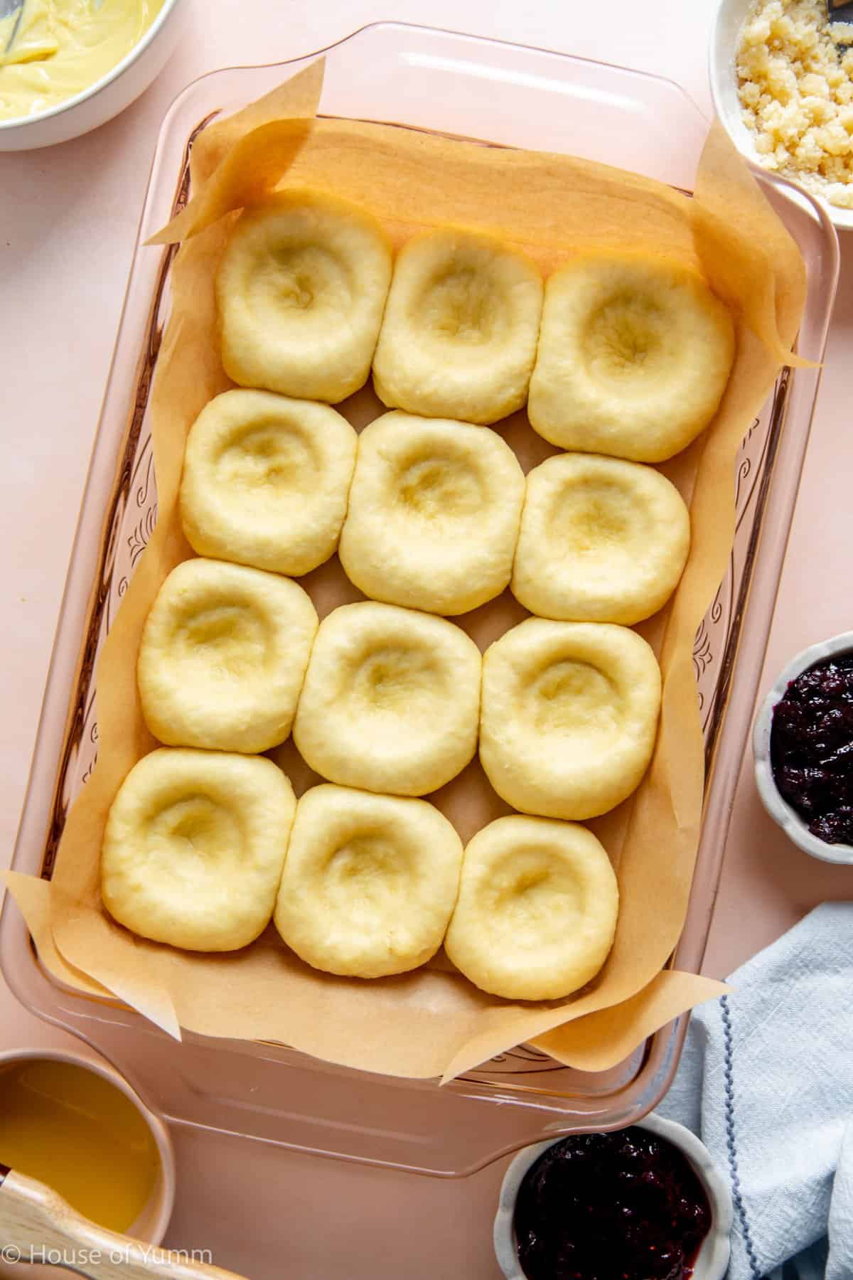 Kolaches shaped and risen with the centers pressed down for filling.
