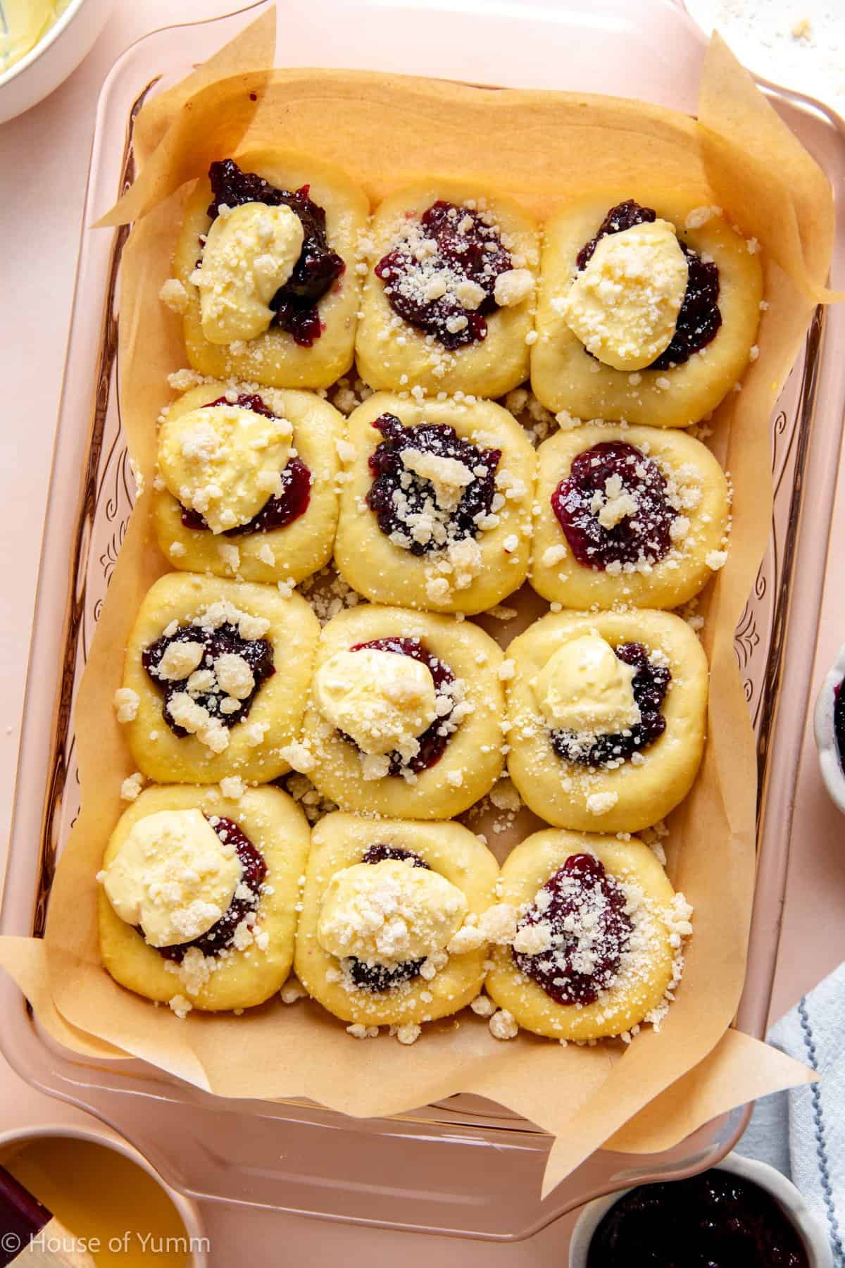 Fruit kolaches with jam filling, cream cheese, and a crumb topping before baking.
