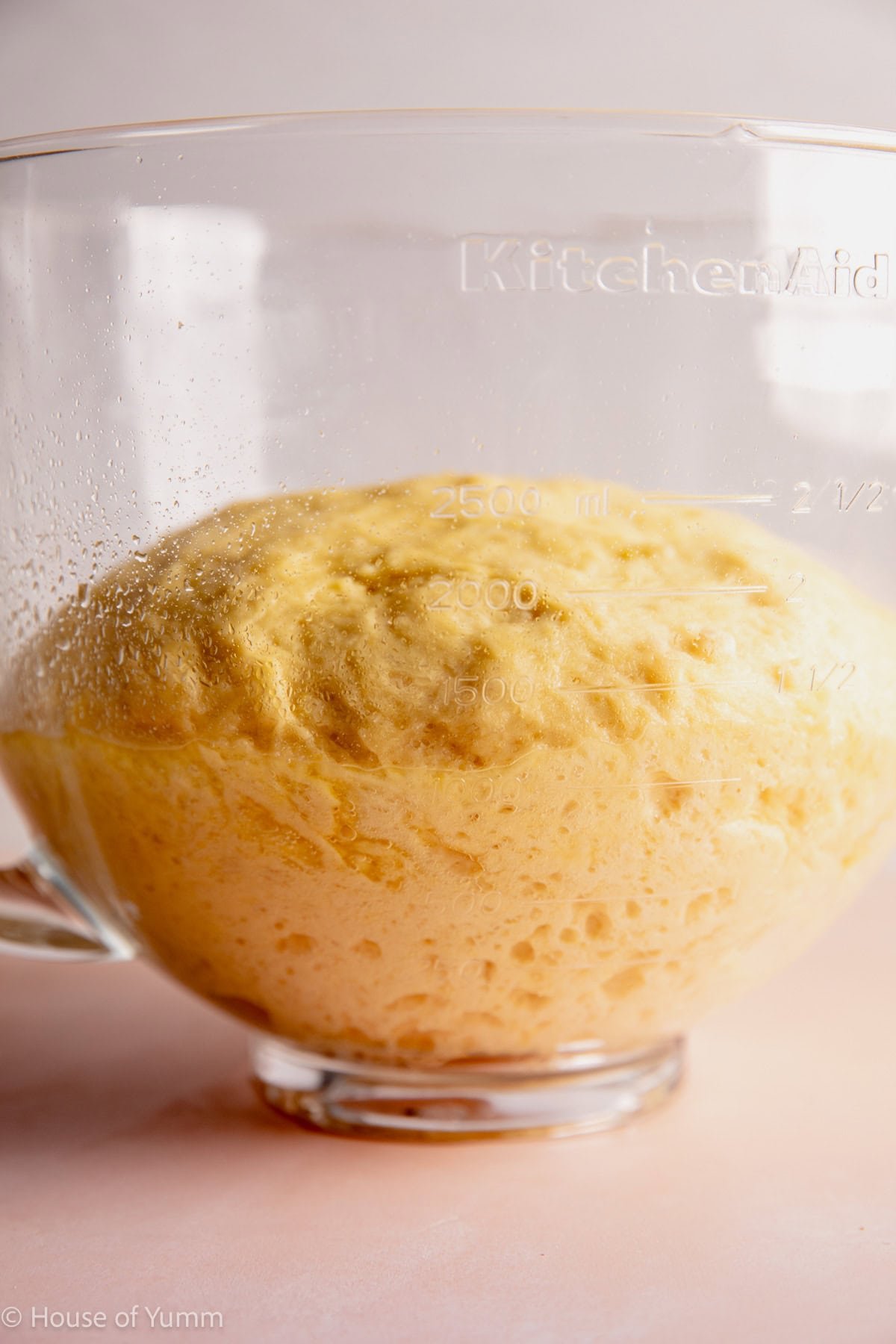 Risen kolache dough in a glass mixing bowl.